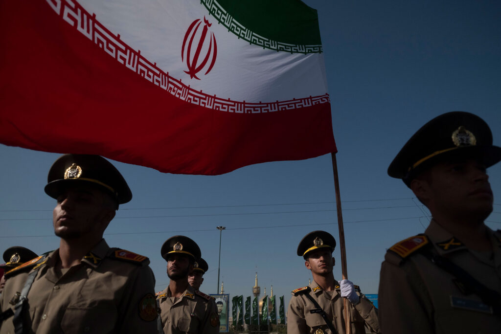 Members of the Iranian Army's land force stand at attention while one of them holds an Iranian flag during a military parade commemorating the anniversary of the Iran-Iraq War (1980-88) outside the Khomeini Shrine in the south of Tehran, Iran, on Sept. 21, 2024.
