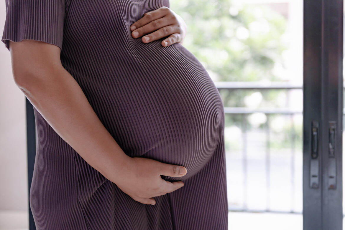 Close-Up midsection of pregnant woman holding her belly. Pregnancy and wellbeing concepts
